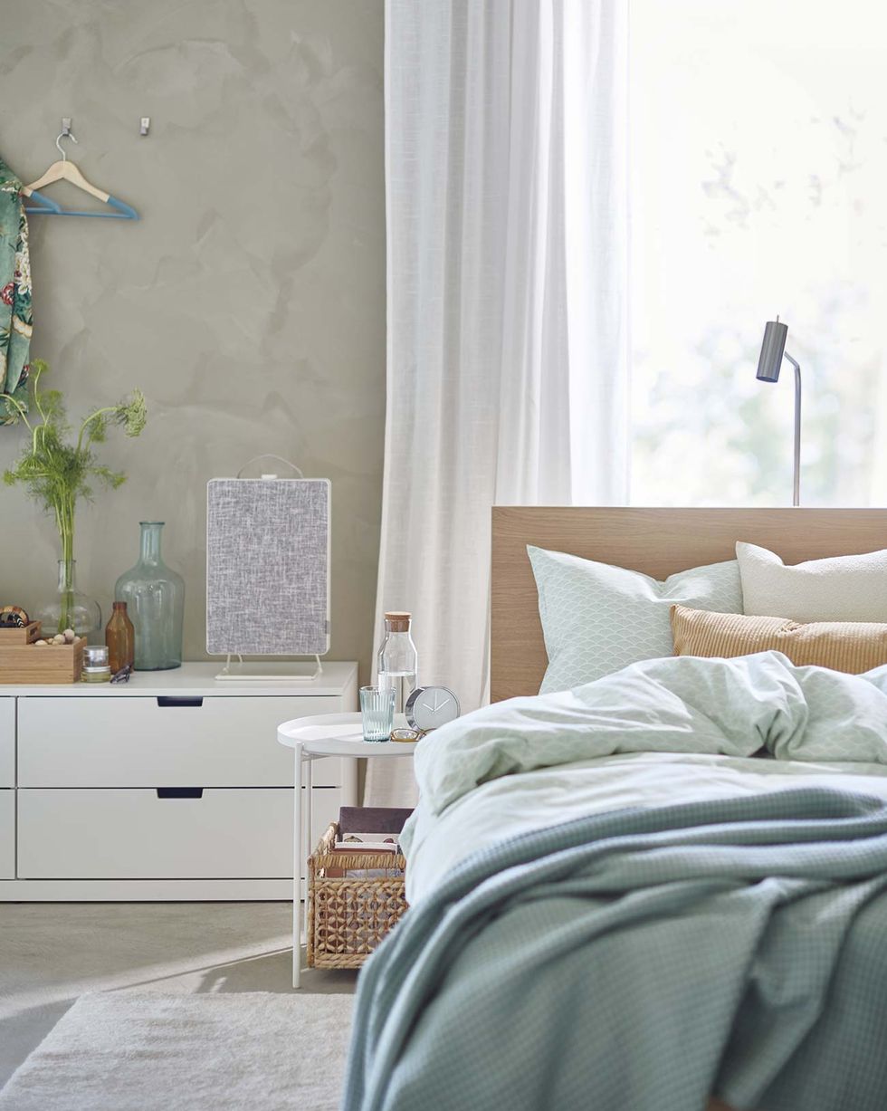 Un dormitorio con paredes blancas y cortinas verdes en los marcos de las  ventanas hay una cama en la habitación