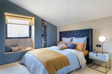 dormitorio abuhardillado decorado en azul con cabecero capitoné