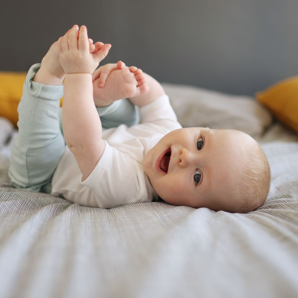 portrait of a smiling baby at home holding their feet