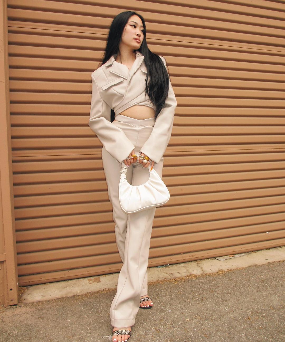 lauren soyung wears a white gabbi bag and beige outfit in front of a brown wall