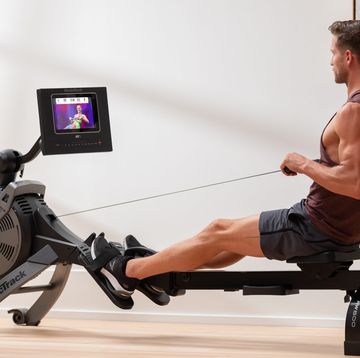 a man sitting on a bench with a weight bar and a tv