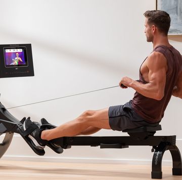a man sitting on a bench with a weight bar and a tv
