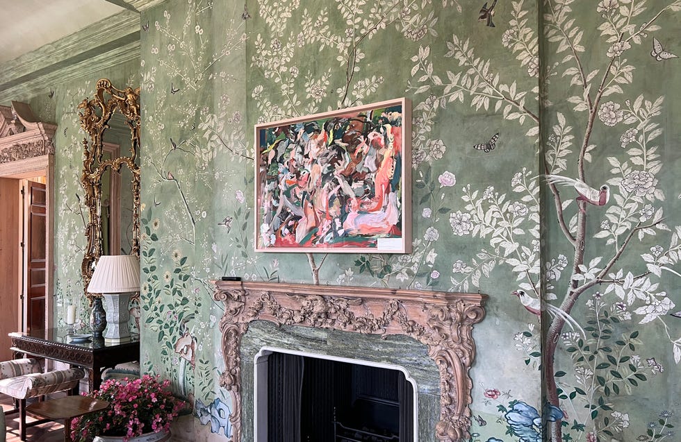 a room featuring green wallpaper decorated with delicate floral patterns and birds, on one wall hangs a colorful painting with abstract figures