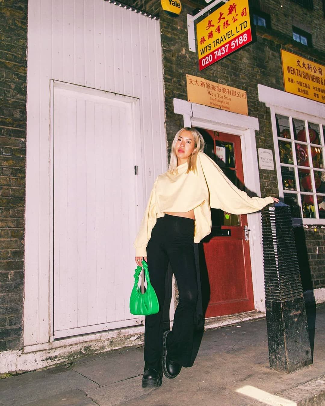 jess cheng from asos holds a green gabbi bag in front of a restaurant