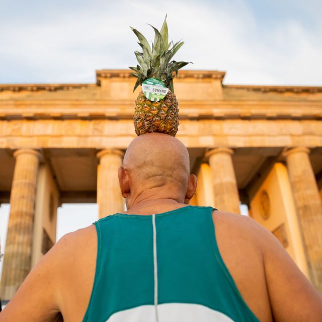 man with pineapple in front of brandenburg gate