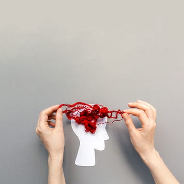 tangled red threads on the silhouette of the head, representing the brain. blue background. flat lay. the concept of mental health and demension
