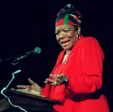 maya angelou wearing a red dress and gesturing with her hands as she reads poetry at a podium