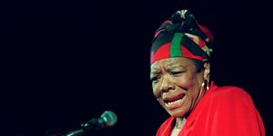 maya angelou wearing a red dress and gesturing with her hands as she reads poetry at a podium