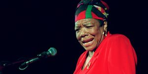 maya angelou wearing a red dress and gesturing with her hands as she reads poetry at a podium