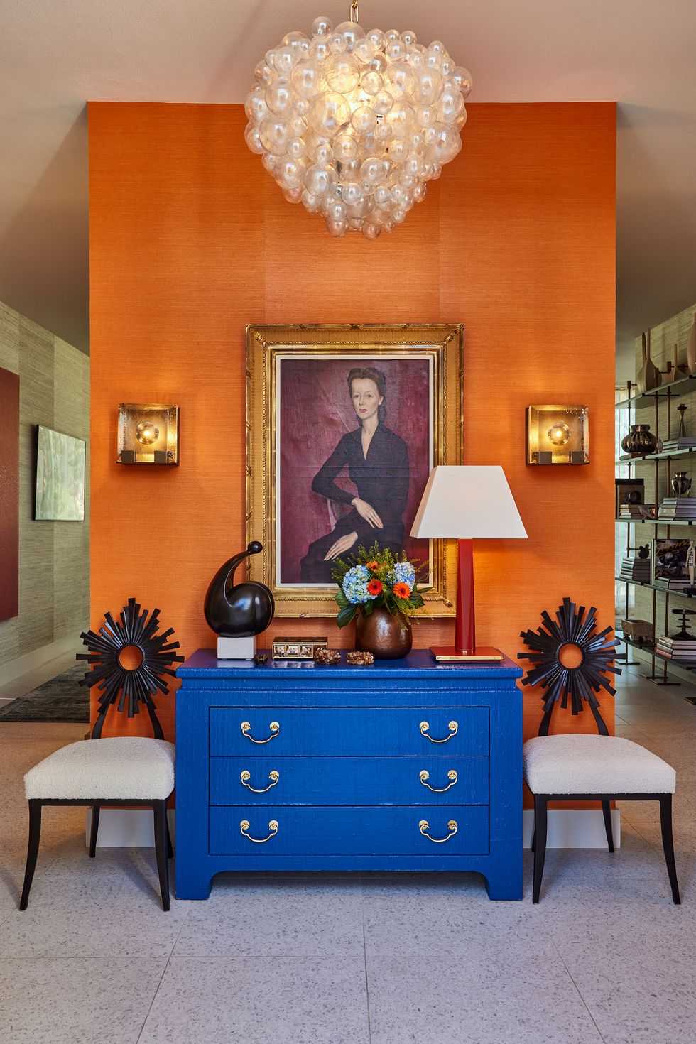 Entrance hall with a blue dresser and a painting on the orange wall