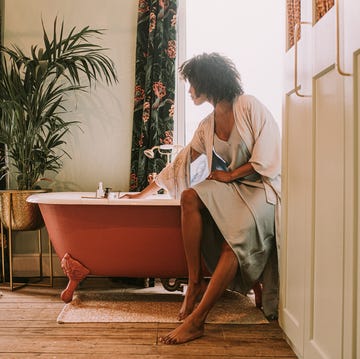 dreamy scene of a beautiful woman perching on the side of a roll top bathtub in a luxurious room