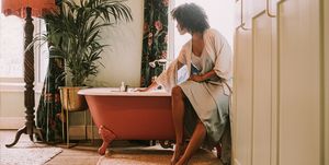 dreamy scene of a beautiful woman perching on the side of a roll top bathtub in a luxurious room