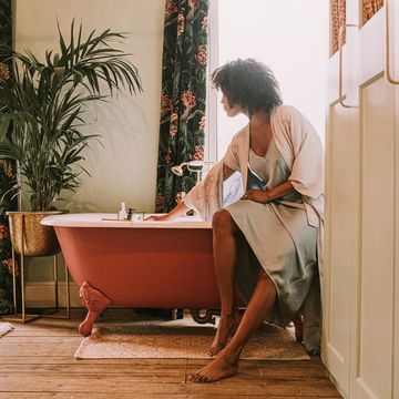 dreamy scene of a beautiful woman perching on the side of a roll top bathtub in a luxurious room