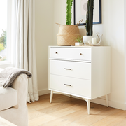 white dresser with cacti on top of it in bright bedroom