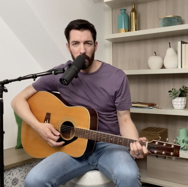 drew scott wearing a purple shirt, playing a guitar, singing into mic