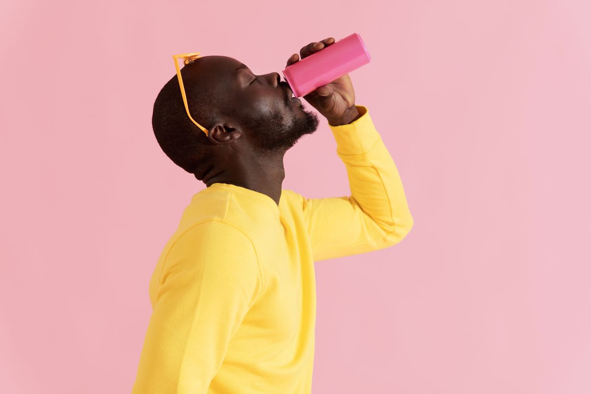 drink black man drinking soft drink on pink background portrait