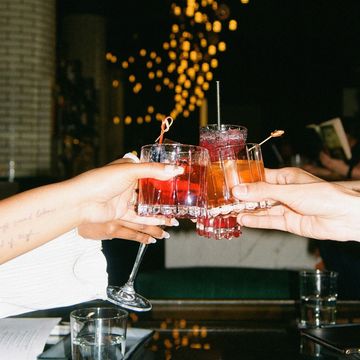 a couple of hands holding glasses with drinks in them