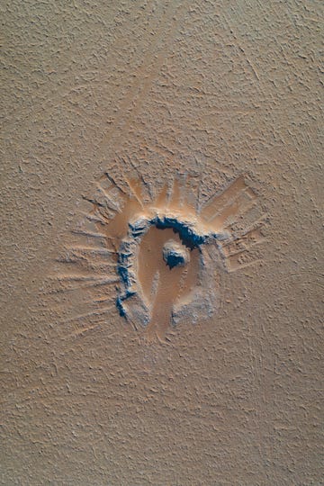 drone shot looking down on an impact crater in the desert, abu dhabi, united arab emirates