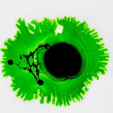 drop of black and green paint slides on a white canvas