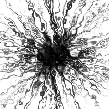black paint spatter in water creating an abstract starlike pattern against white background