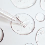 drop of gel or serum with air bubbles flow out from a pipette near other drops on a pastel white background