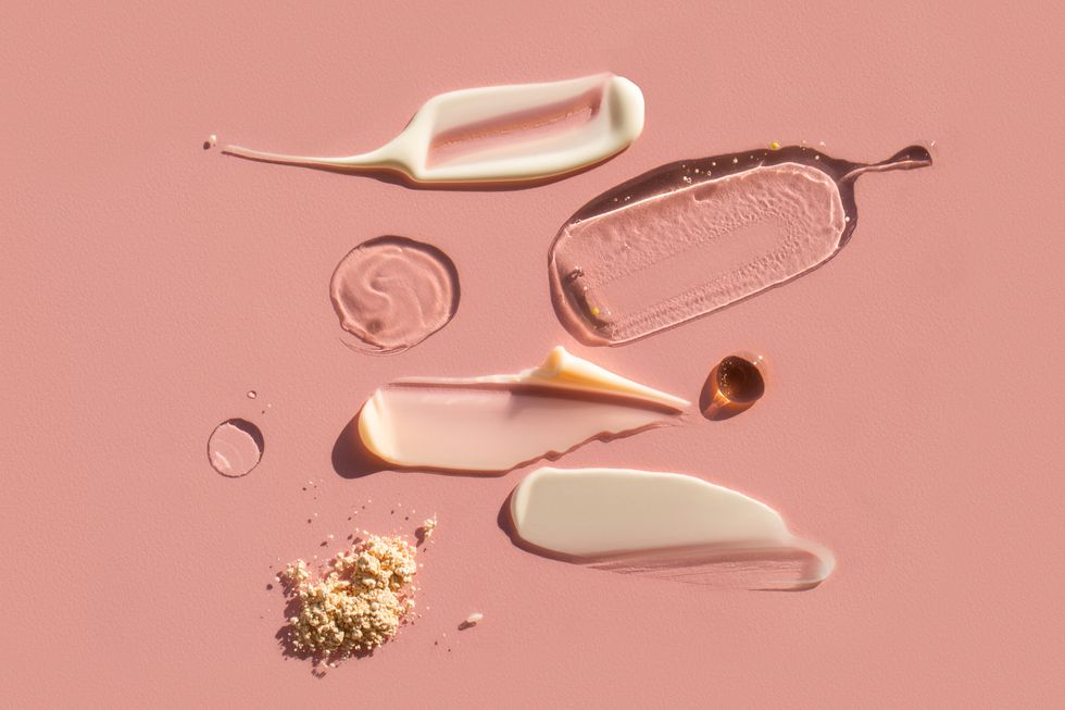 drops and smears of various cosmetic products on pink background trendy selfcare products of the year