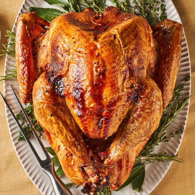 dry brine full turkey sitting on a white platter on top of fresh herbs