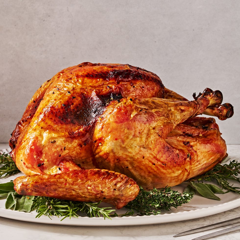 Fresh whole turkey on white background with herbs. Thanksgiving