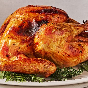 dry brine full turkey sitting on a white platter on top of fresh herbs