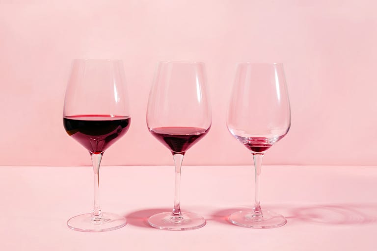 mindful drinking and alcohol cutback concept three glasses with lowering levels of red wine poured, isolated on pink background
