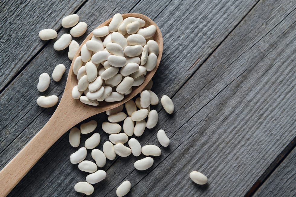 dry red beans on a wooden spoon and on a blue ceramic plate, on the background of the table vegetarian and vegan food