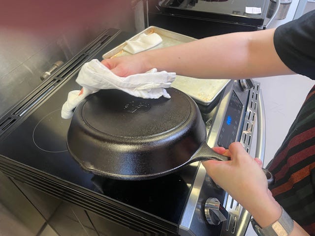 person using a towel to dry a cast iron skillet