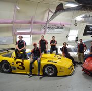 casey putsch sits on the corvette hood race car with his students surrounding him