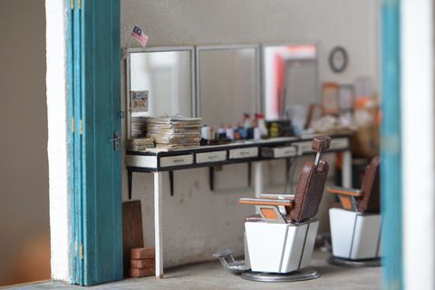 miniature replica of barber shop with three mirrors, two barbershop chairs, and counters containing barber supplies