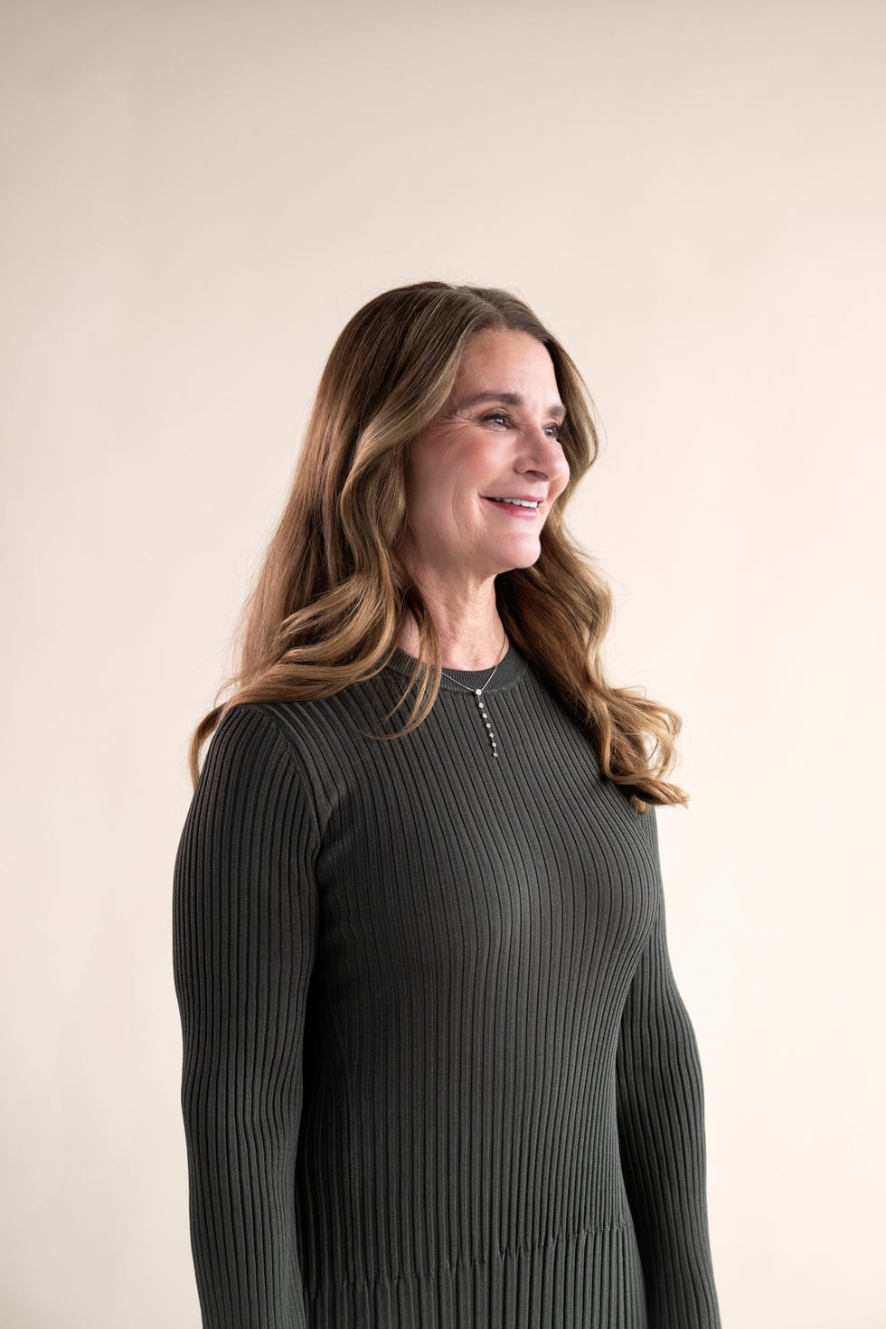 individual dressed in a dark ribbed longsleeve dress against a neutral background