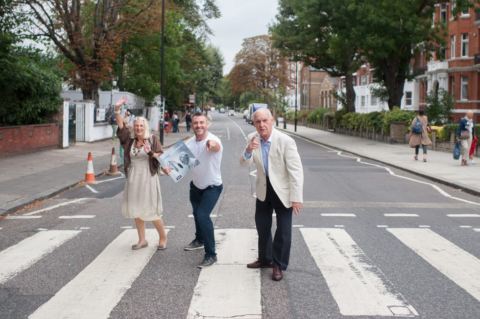 Three individuals posing in a crosswalk with a sign