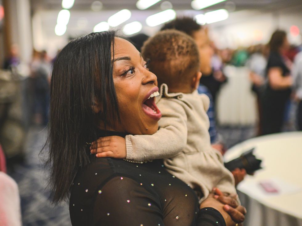 a woman with her mouth open excitedly, while holding a baby