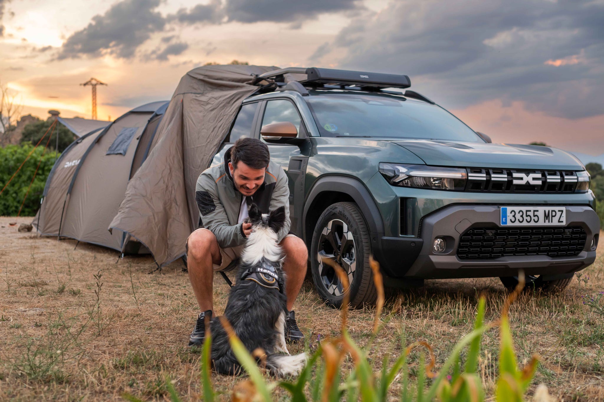 a person interacting with a dog near a camping setup and vehicle