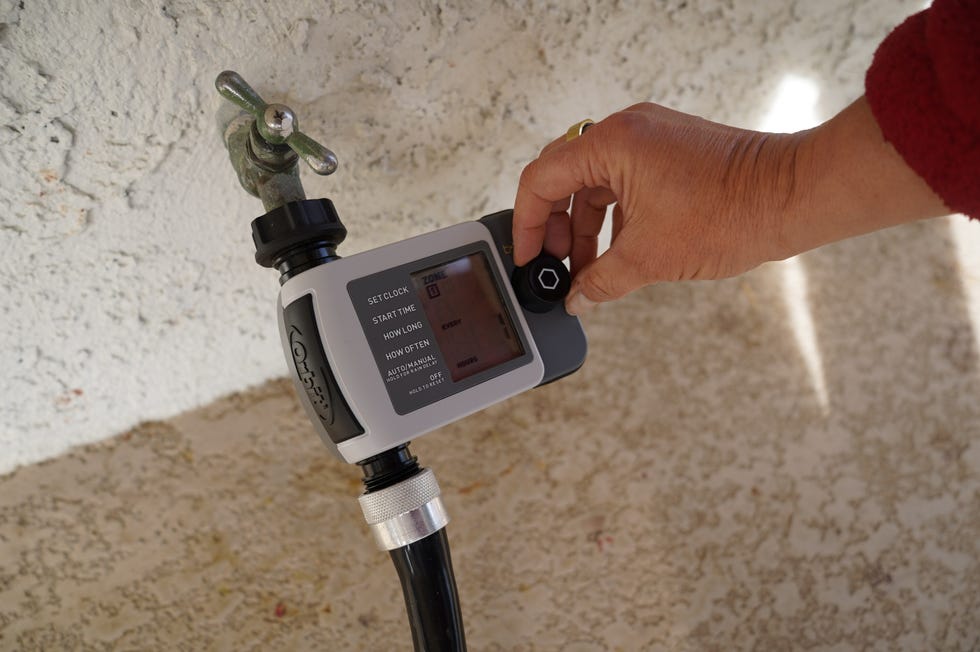 a person adjusts the setting on a garden hose timer