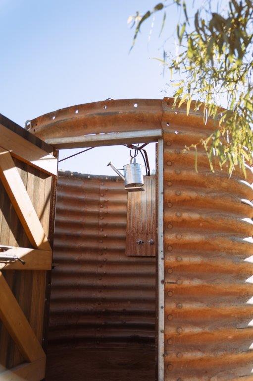 a grain silo as outdoor shower with a watering can as the faucet