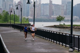 runners jogging on a park path over water with a city in the background
