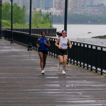 Runners jogging on a park path over water with a city in the background runners jogging on a park path over water with a city in the background
