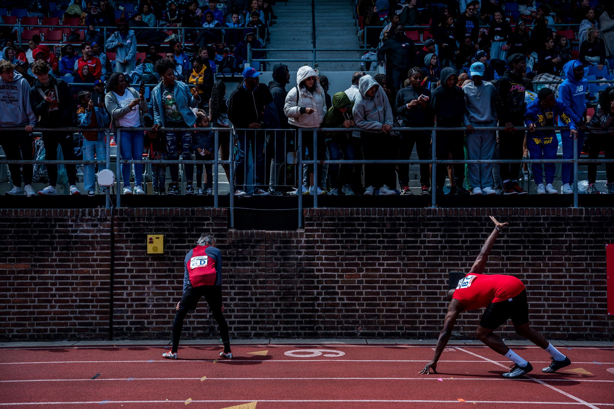 a runner raises his hand to grab a baton in a relay race