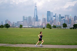 runner speeding down a paved path with new york city in the background