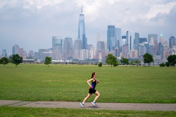 runner speeding down a paved path with new york city in the background