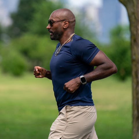 RWD A person jogging in a green park setting with a city skyline in the background