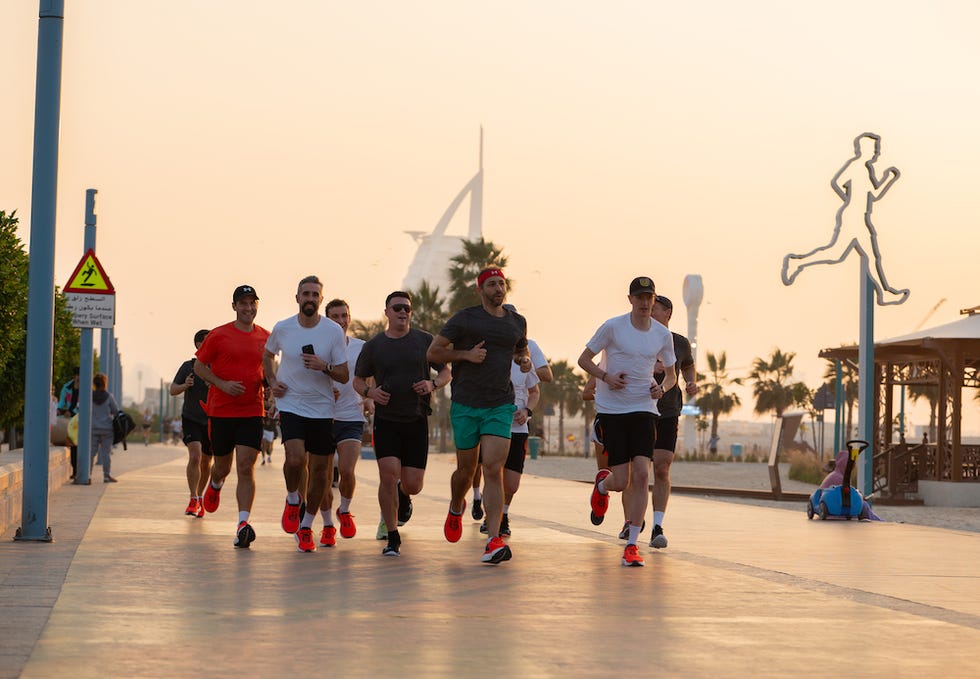 group of runners jogging along a promenade at sunset
