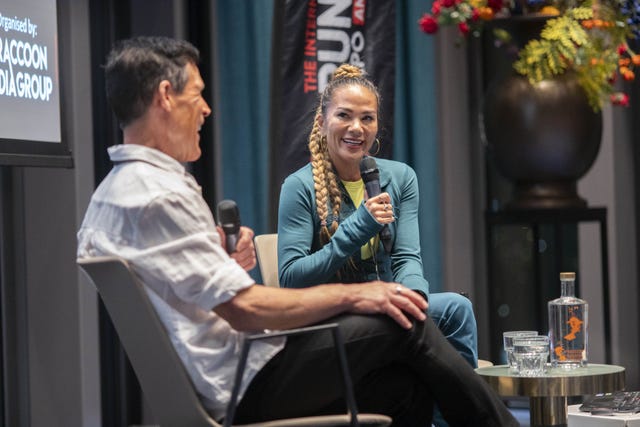 two people with microphones sitting by a table at a conference