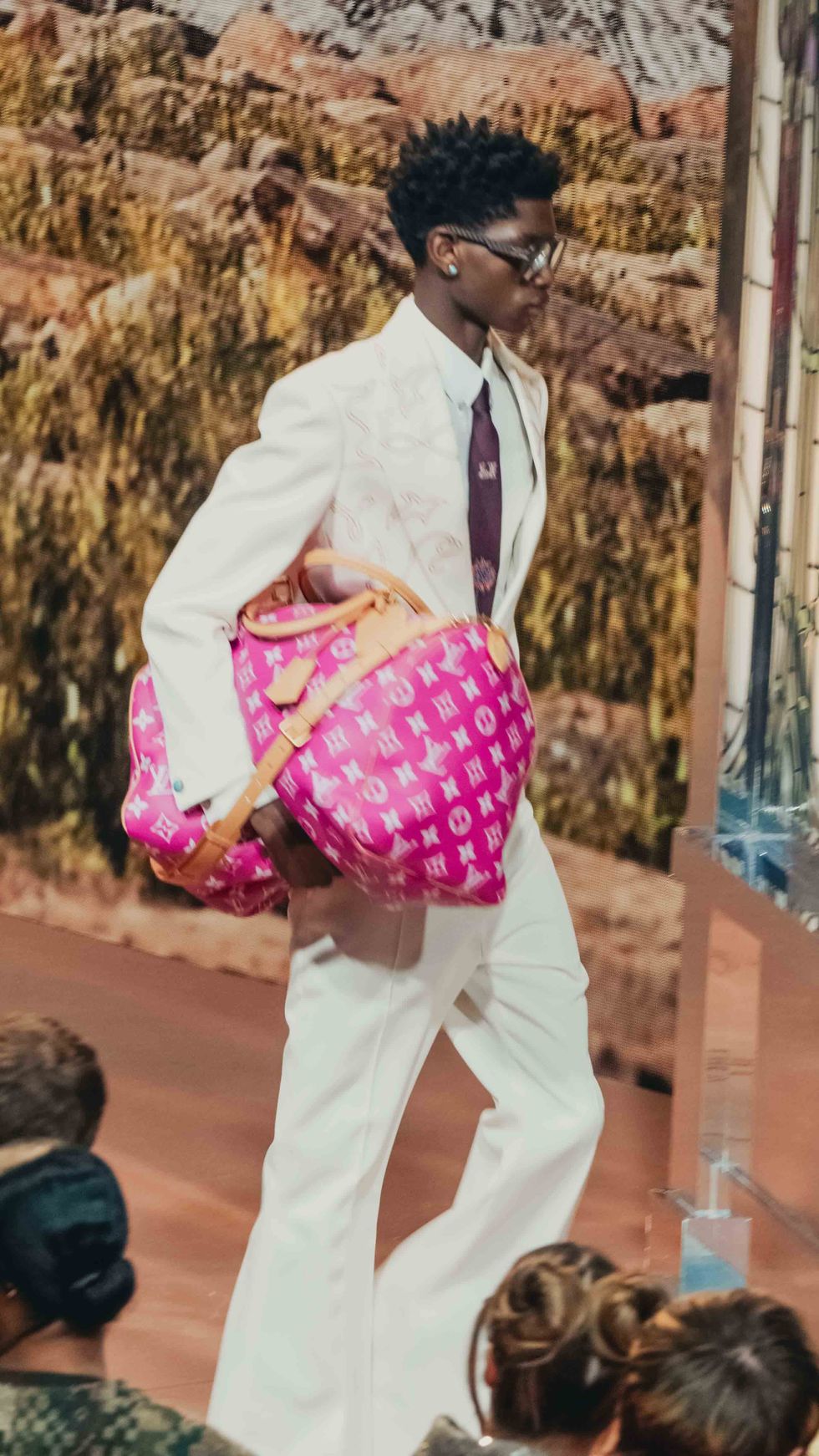 a man in a suit and tie carrying a pink bag