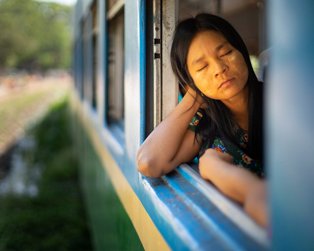 een vrouw in een trein in yangon met thanaka op haar gezicht